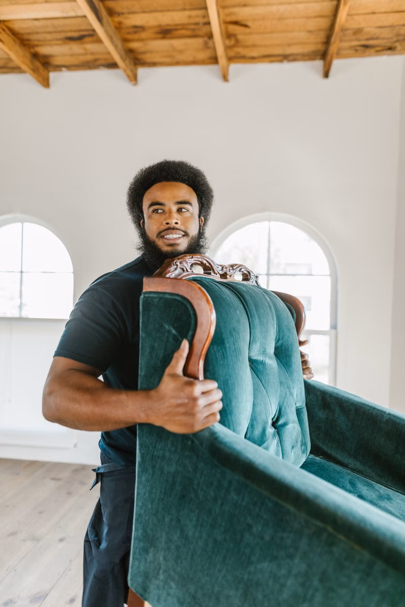 Junk removal workers carrying unwanted furniture for same-day pickup